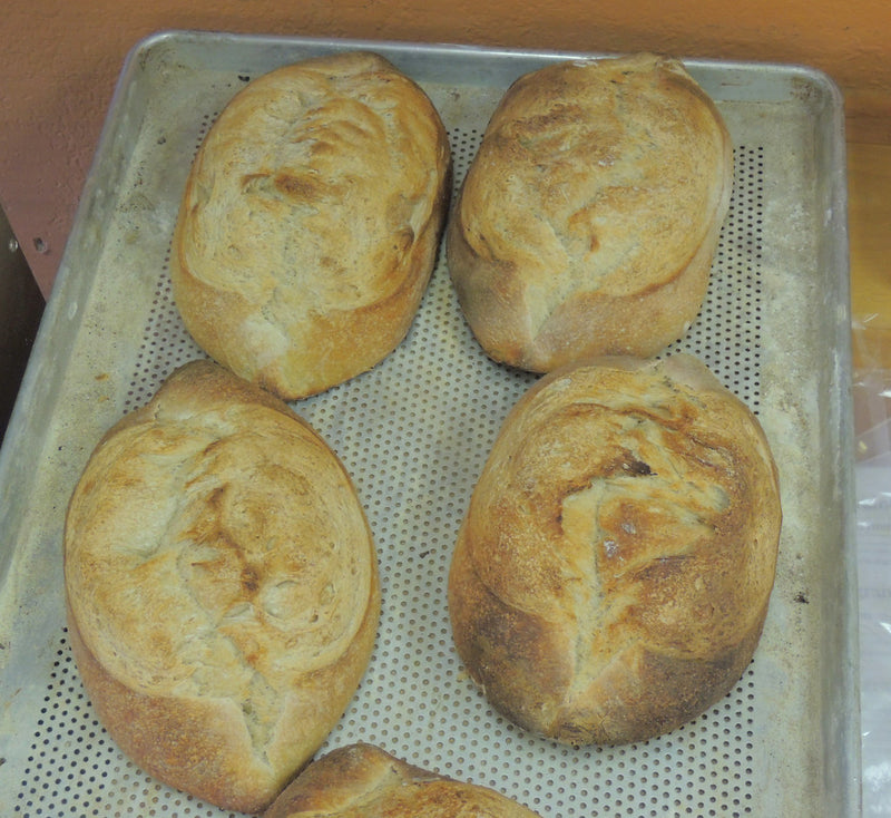 Freshly baked round sourdough loaves cooling on a bakery tray