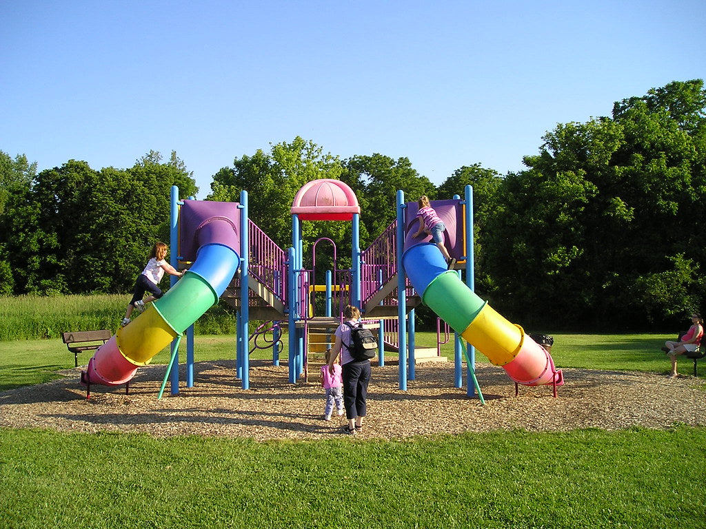 Children playing at a colorful playground in a grassy park