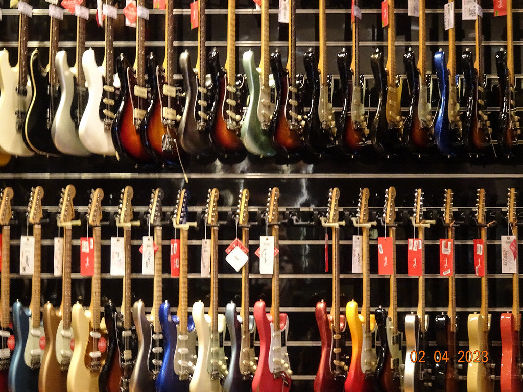 Rows of colorful electric guitars hanging on display racks in a music instrument shop
