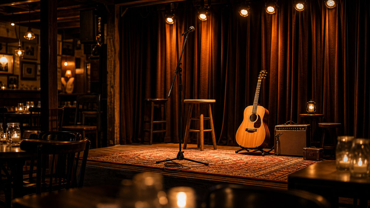 An empty microphone and acoustic guitar on a warmly lit small music venue stage.